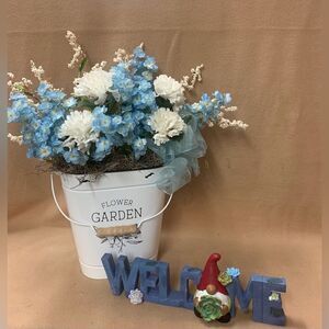 Blue and white flowers in white can.  Also a Welcome sign.  Inv 485